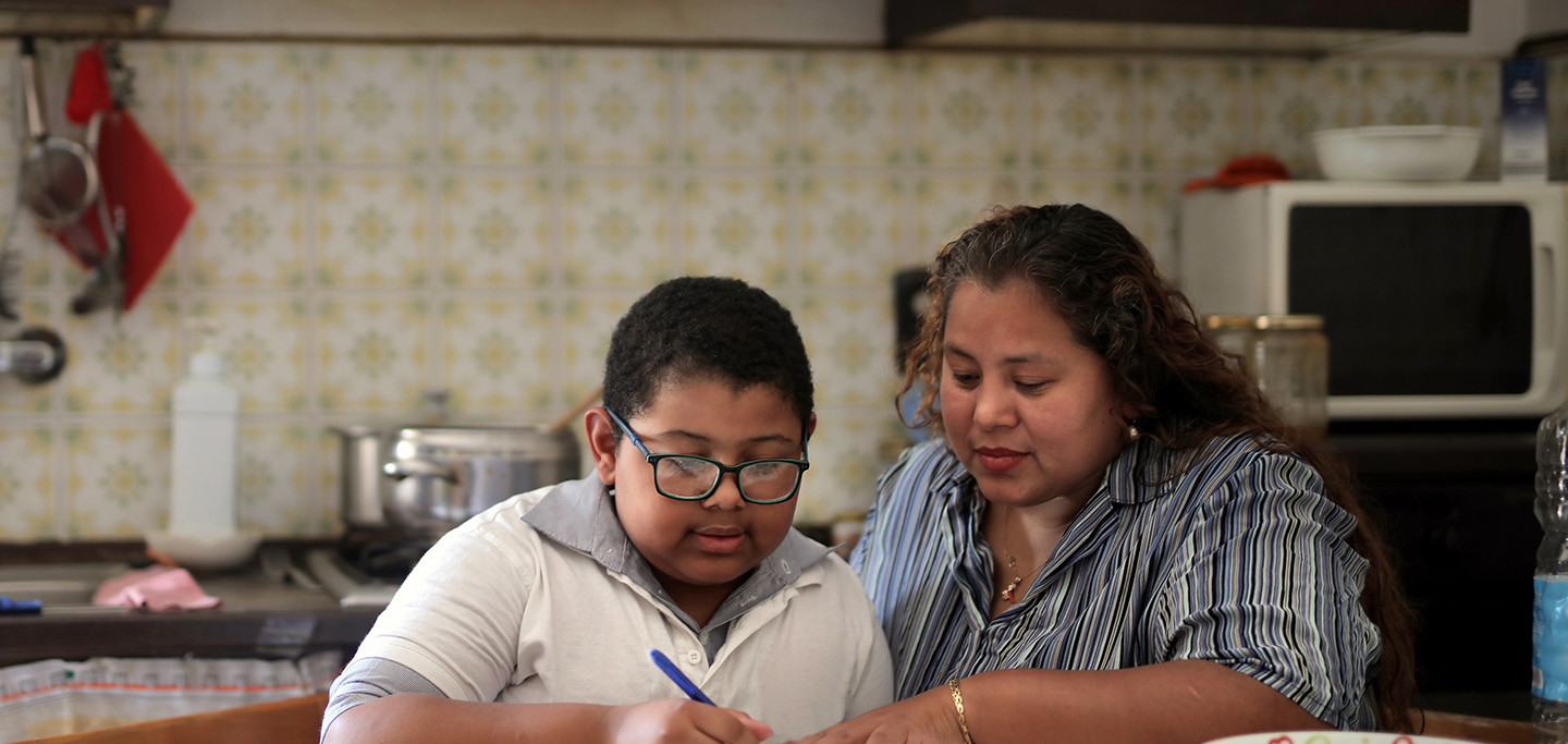 Child and mother working on homework in kitchen