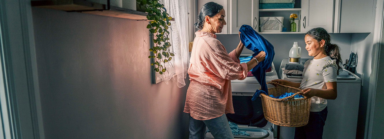 Mother and daughter folding laundry in laundry room